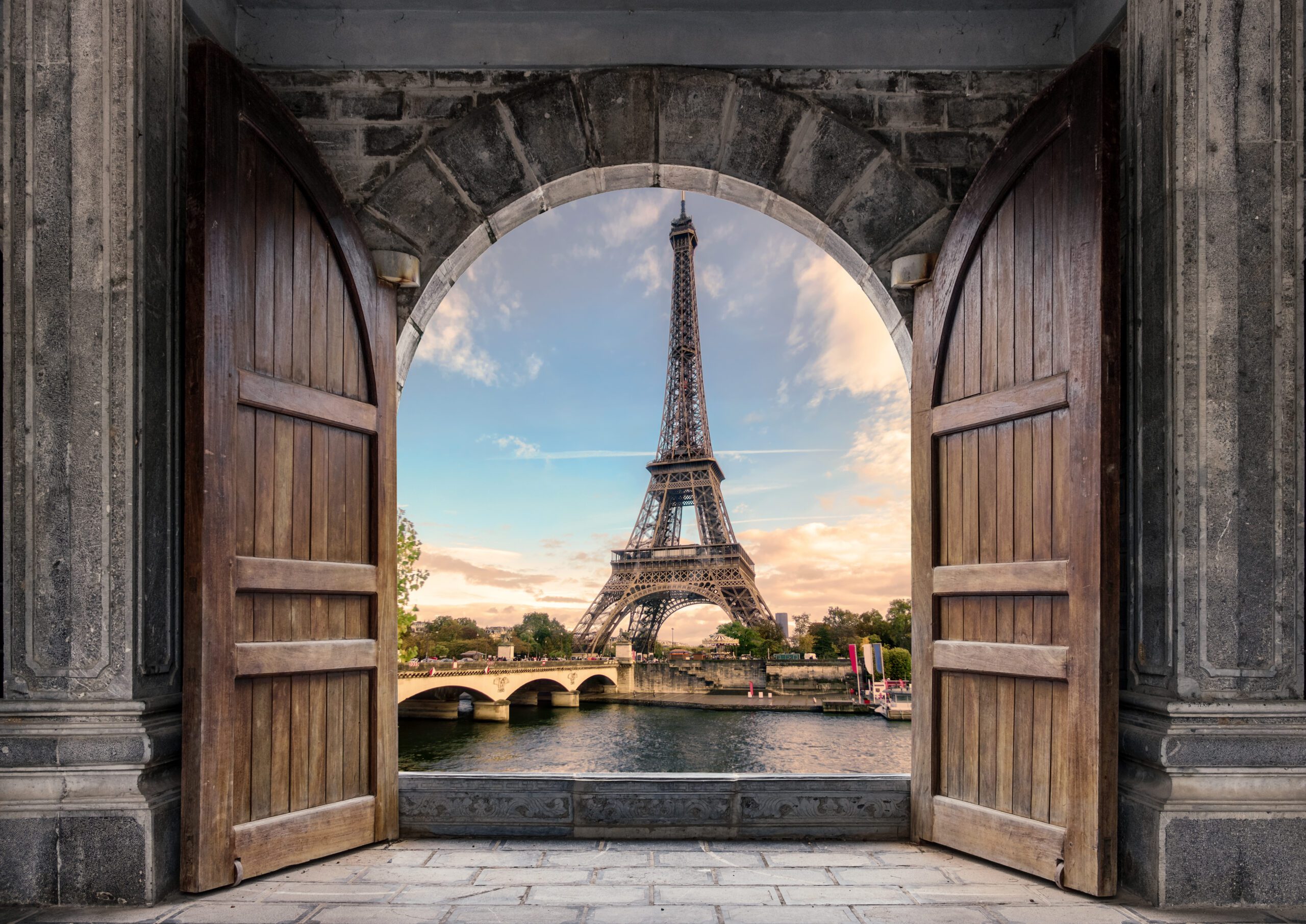 Large wooden door open with Eiffel Tower on Seine River on sunse