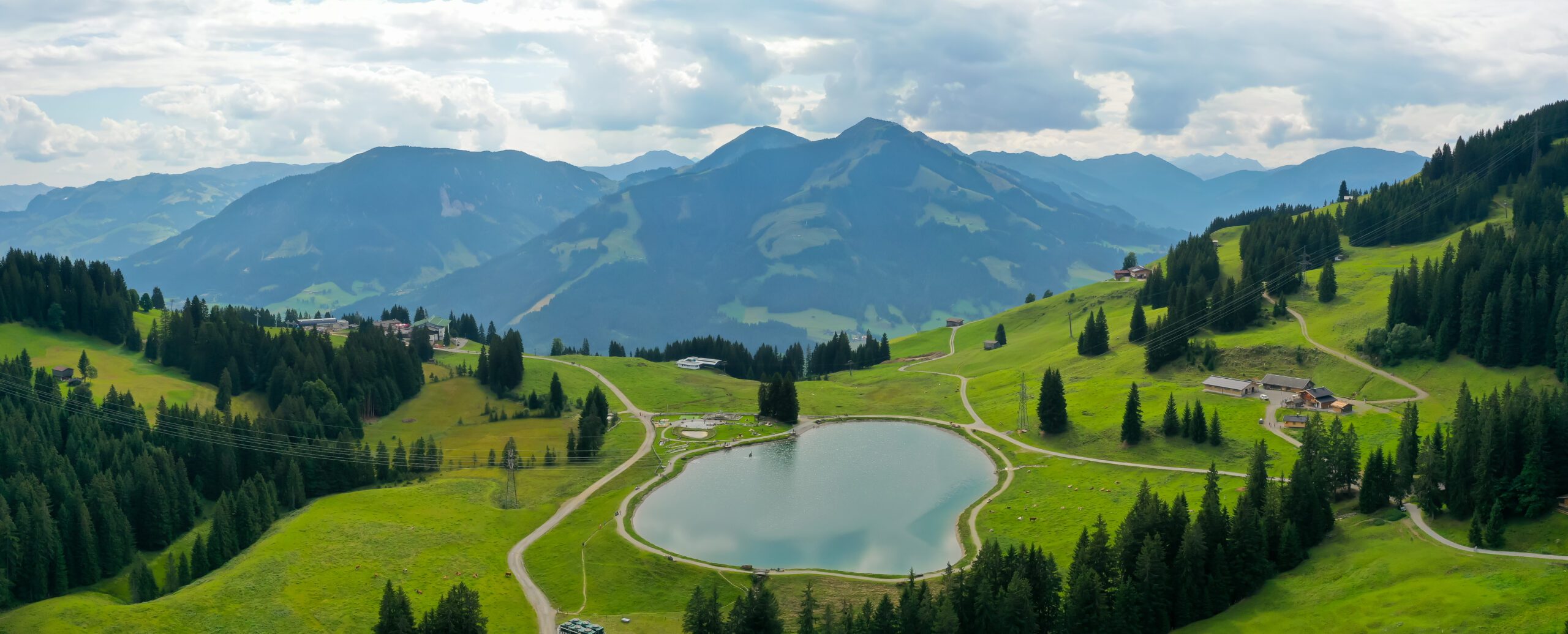 Panoramic shot of the Filzalmsee surrounded by hills covered in greenery in Austria