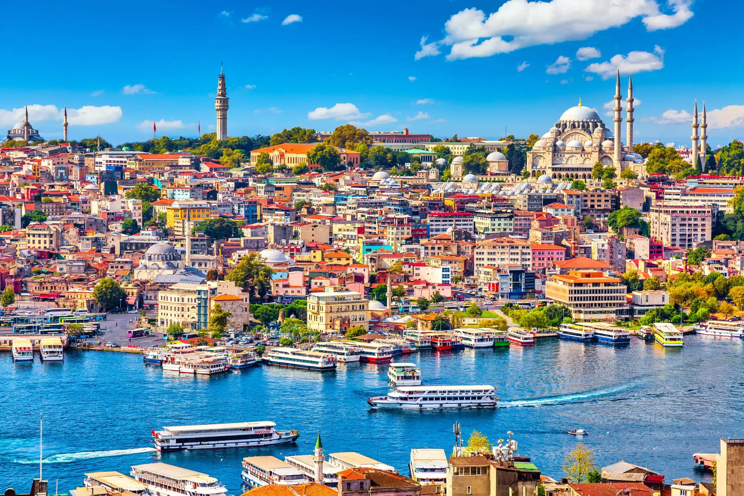 Touristic sightseeing ships in Golden Horn bay of Istanbul and mosque with Sultanahmet district against blue sky and clouds. Istanbul, Turkey during sunny summer day.