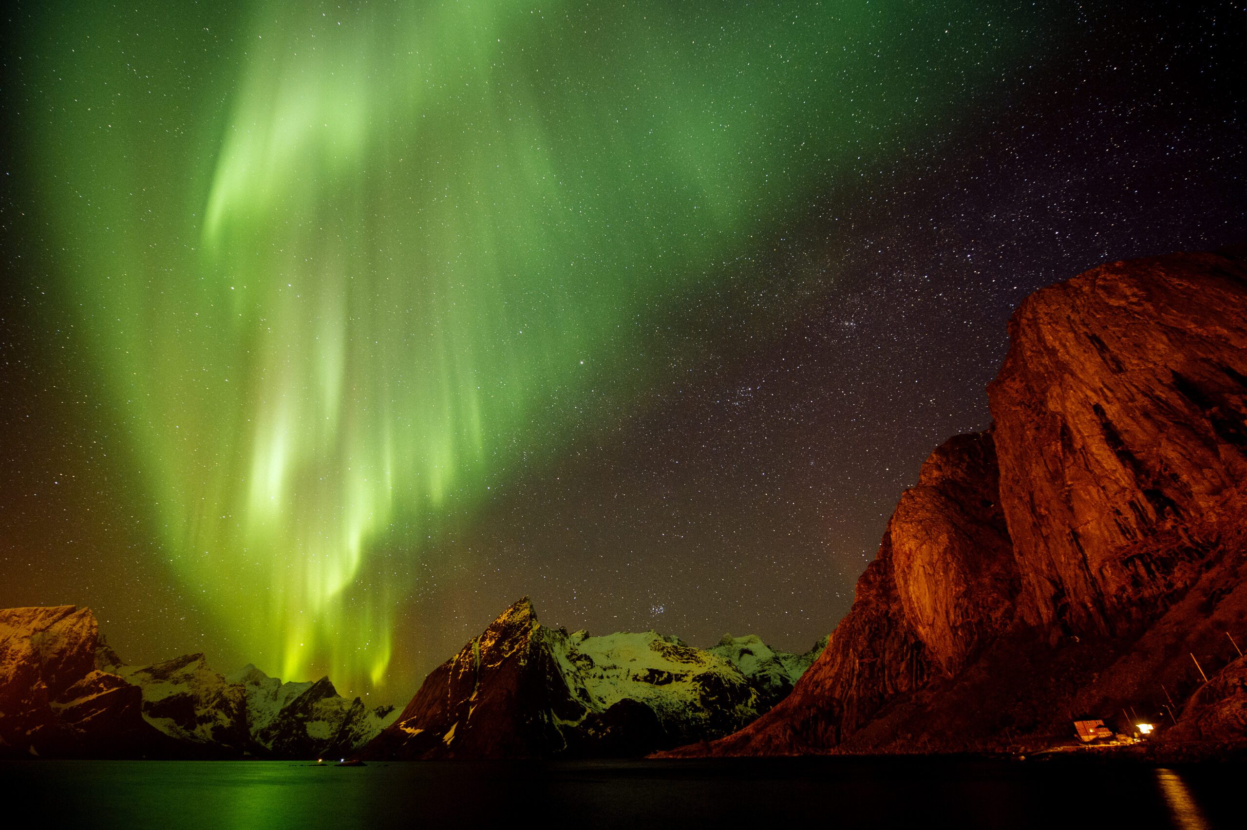 View of aurora borealis over sea and snow capped mountains, Reine, Norway